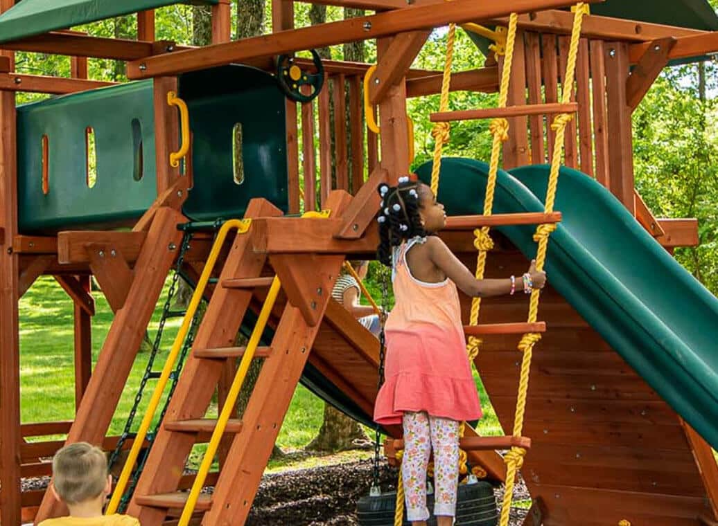 Girl standing and grabbing rope ladder on a Woodplay outdoor playset